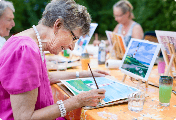 A woman does a watercolor painting of a lighthouse