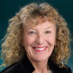 portrait of smiling woman with blonde, curly hair in a black top