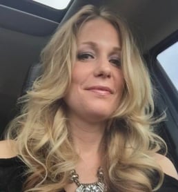 woman looking down at camera in a car with curled blonde hair