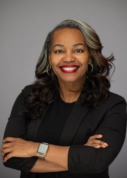 portrait of smiling woman in all black, arms crossed, wearing a smart watch