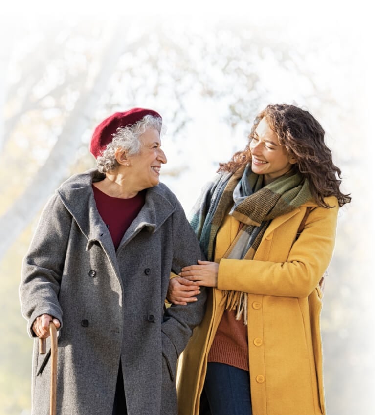 A caregiver and resident take a walk together on a crisp fall day