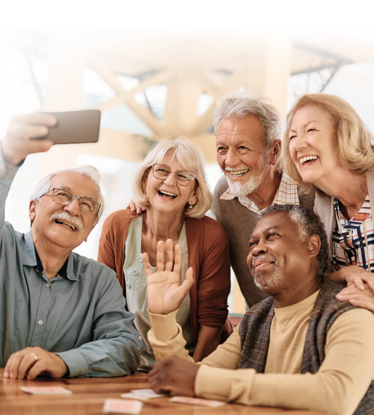 A group of elderly friends smile for a selfie